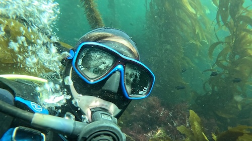 Me in SCUBA gear underwater with kelp in the background